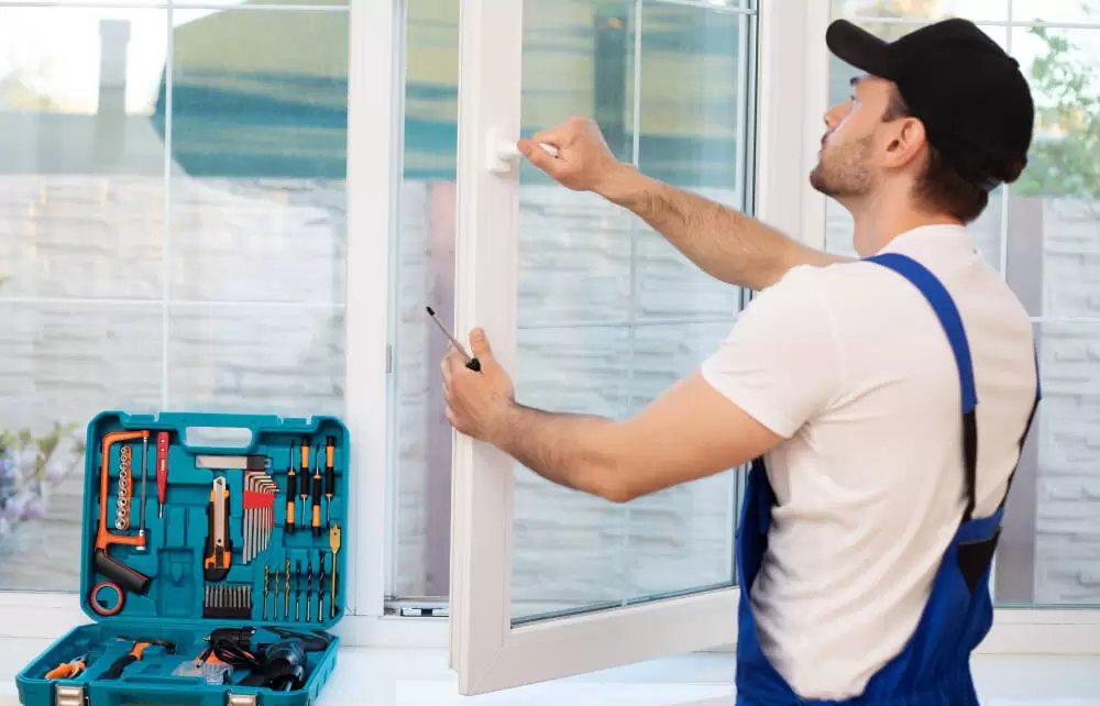 Professional window installer measuring white vinyl sliding door for replacement installation with tool kit