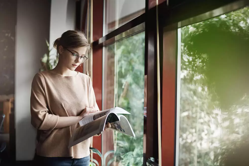 Woman opening white vinyl casement window in modern home interior