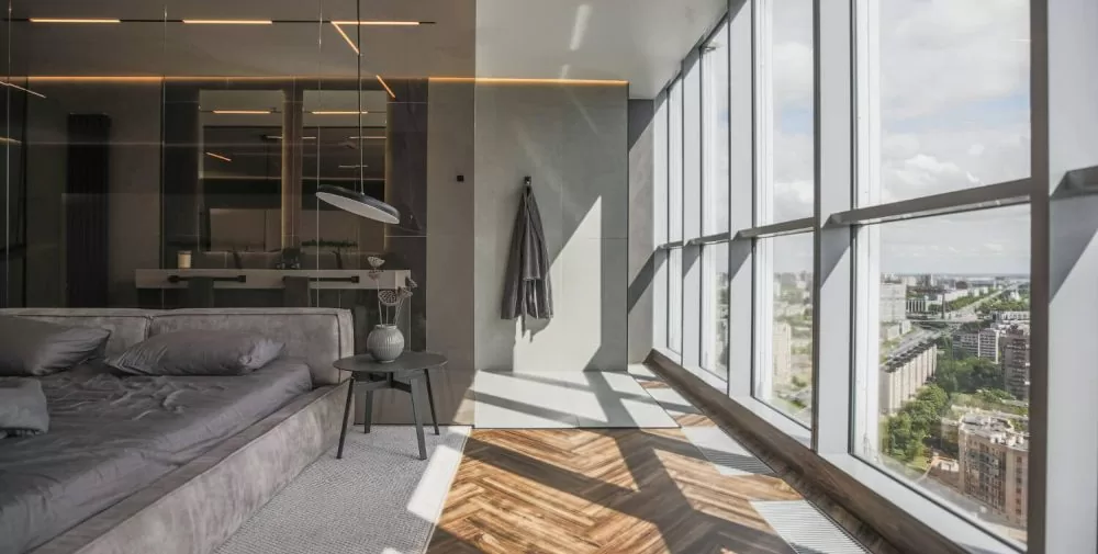 Modern bedroom with floor-to-ceiling black frame casement windows providing city and mountain views