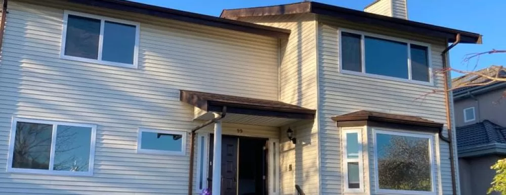 Beige siding two-story house with new white frame windows and bay window in Vancouver neighborhood